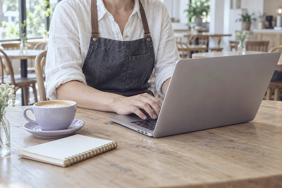 Pemilik restoran membuka laptop di meja kafe